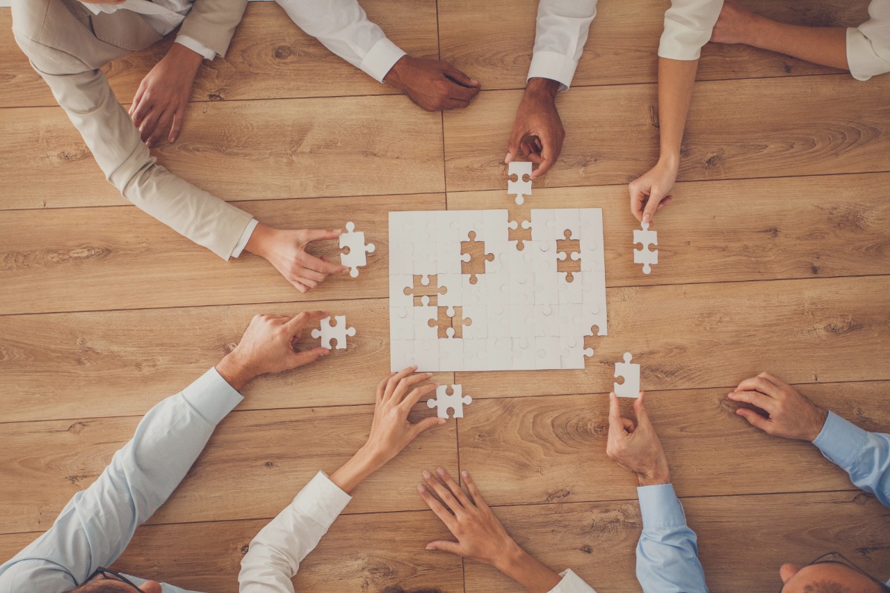 ESG i Etyka - Grupa ORLEN. Ludzie układający puzzle dążą do osiągniecia wspólnego celu.